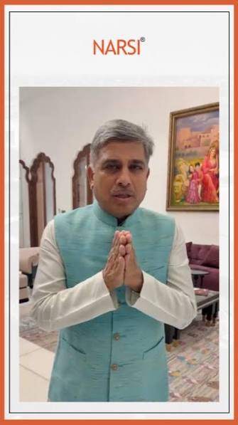 Narsi Kularia in a pale turquoise bandhgala, hands folded in namaste, inside a frame branded NARSI