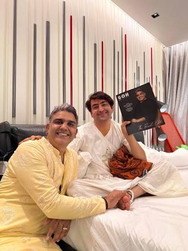 Narsi Kularia in a yellow embroidered kurta, smiling with his arm around a younger man in white who holds up a copy of SON magazine